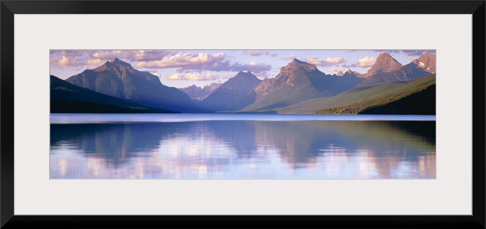 Oversized, horizontal photograph of mountains reflecting in the calm waters of Lake McDonald in Glacier National Park, Mon...