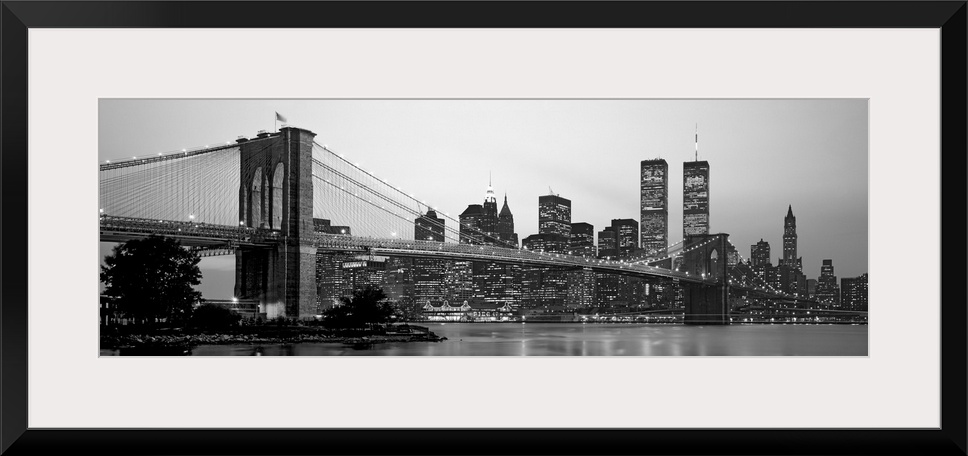 Panoramic photograph of the Brooklyn Bridge against a skyline filled with skyscrapers in New York.  The buildings and brid...