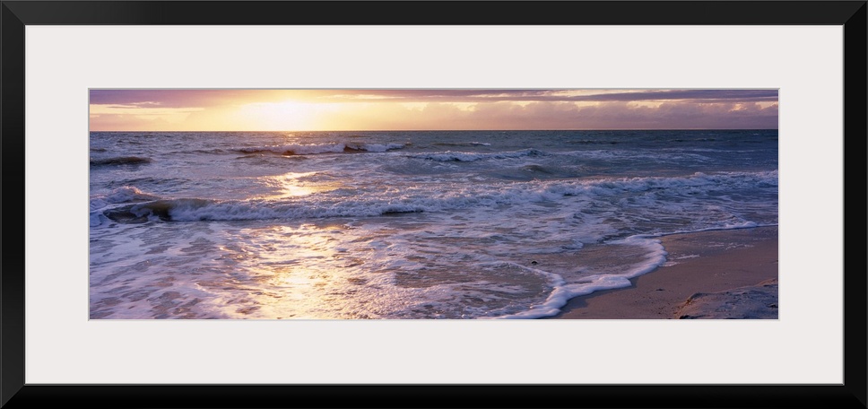 Panoramic photograph of a sunset on a sandy beach in the Gulf of Mexico located within Florida.  The bright light of the s...