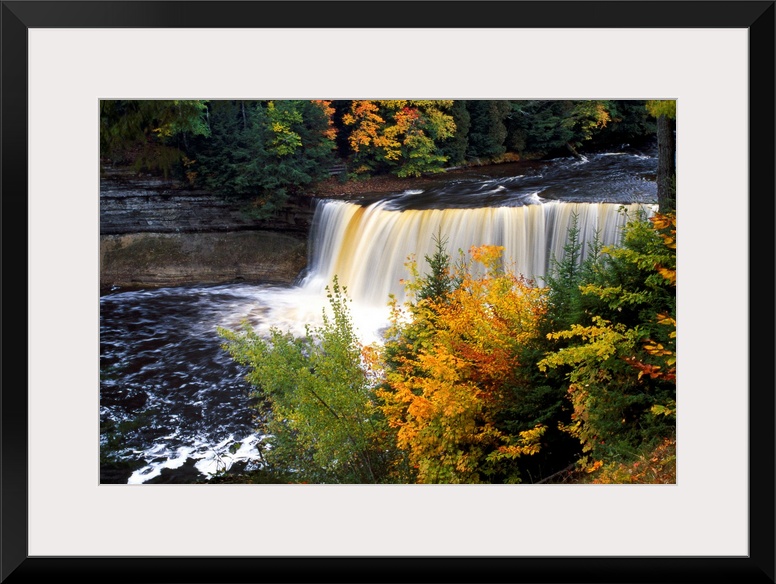 Giant, horizontal photograph of Tahquamenon Falls surrounded by colorful fall foliage in Michigan.