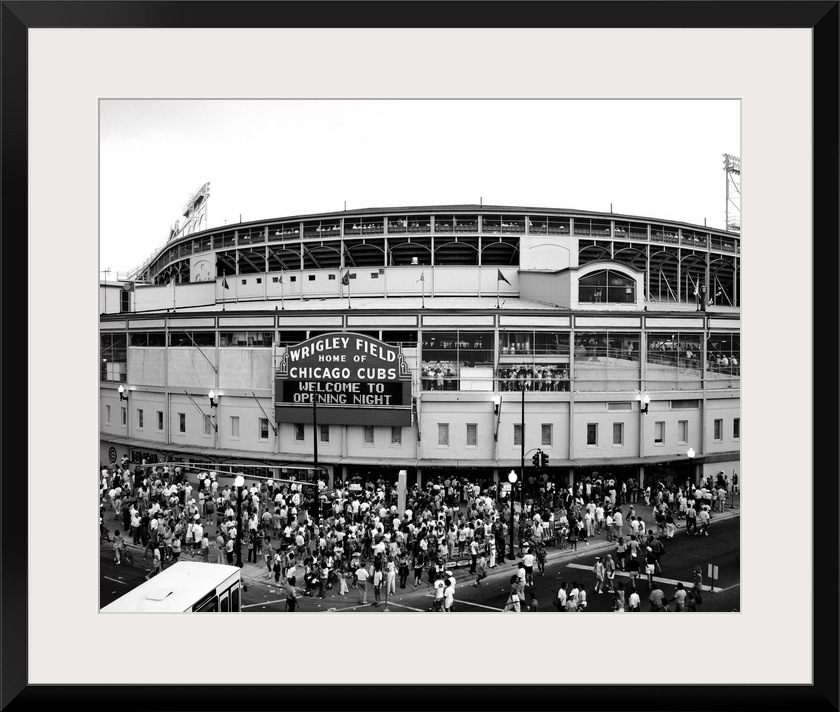 A black and white photograph taken outside of the Chicago Cubs stadium as fans are shown entering for the first game of th...
