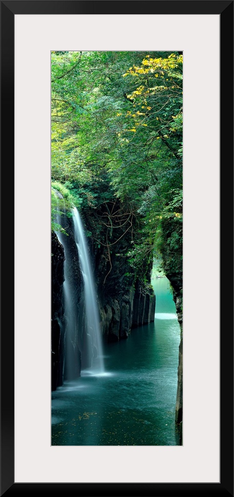 Vertical outdoor shot of a forest, river, and waterfall taken with time-lapsed photography.