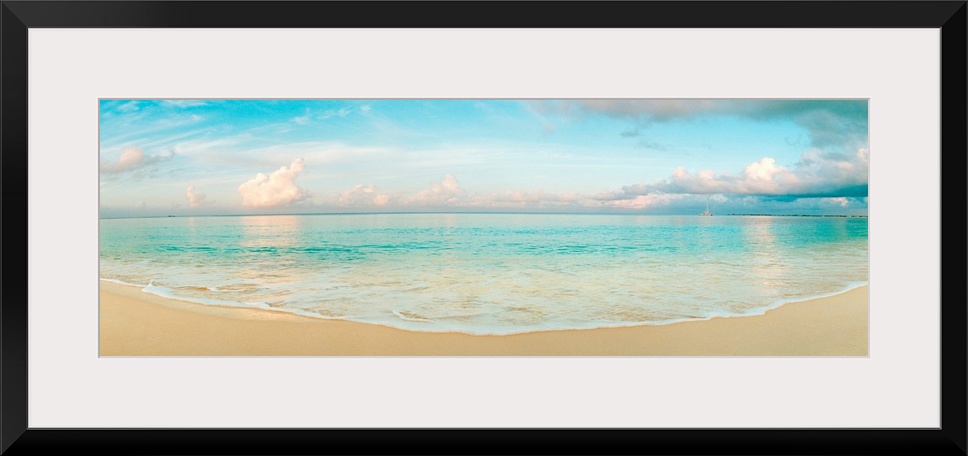 A wide angle panoramic wall hanging of a calm tropical ocean, waves on the beach, and cumulus clouds near the horizon.