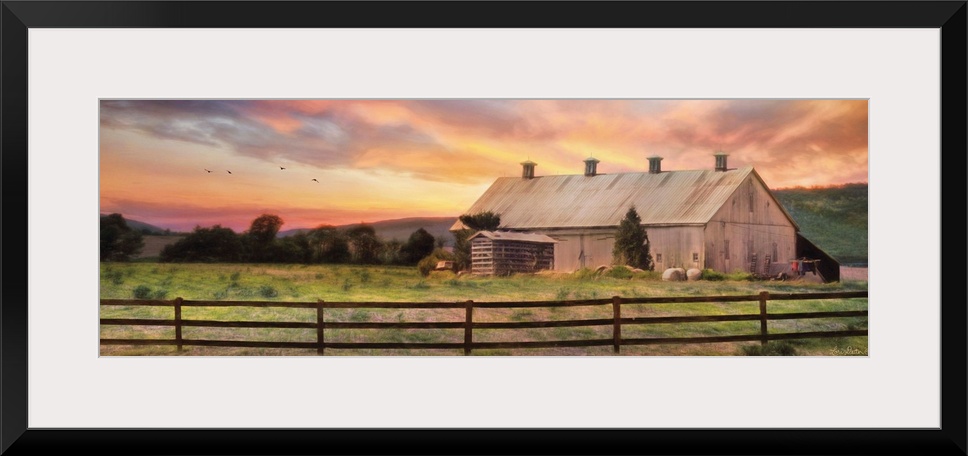 A barn in the countryside with a wooden fence in the early evening.