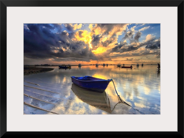 A blue boat docked in shallow water at sunrise, Semawang Beach, Bali.