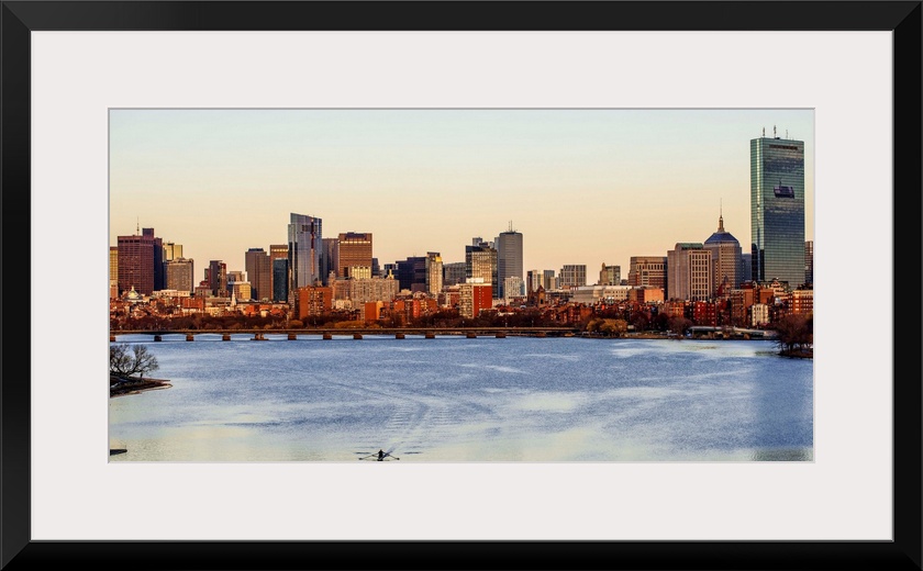 Panoramic view of the Boston City skyline at sunset, seen from across the water.