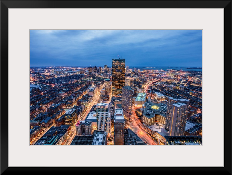 View from a skyscraper of tall buildings in Boston glowing at night.