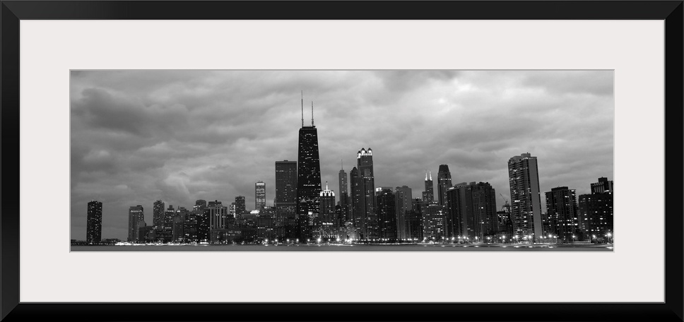 Panoramic view of the Chicago city skyline illuminated in the early evening, seen from across the water.