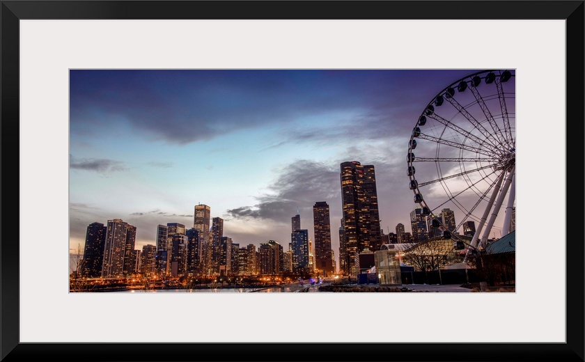 View of the Chicago city skyline illuminated in the early evening with a Ferris Wheel in the foreground.