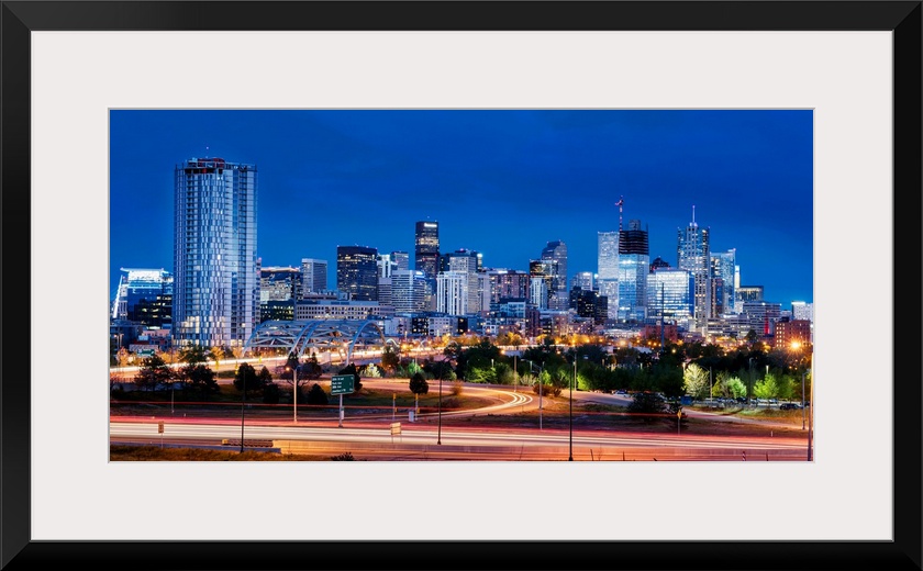 Photo of Denver's skyline at night with light trails.