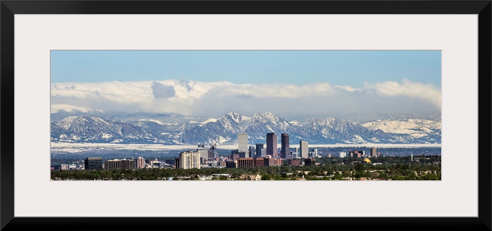 Panoramic photo of a Denver skyline against a backdrop of the Rocky Mountains.