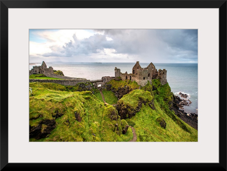 Landscape photograph of Dunluce Castle next to the ocean, taken from a higher point.