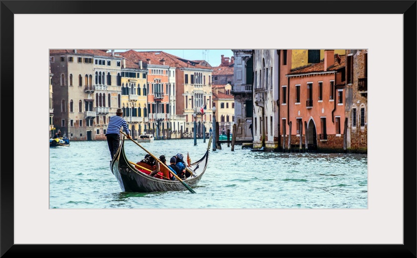 Photograph of the rear side of a gondola rowing through Grand Canal in Venice.