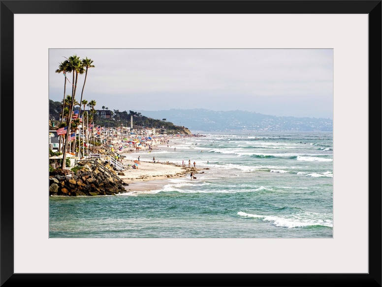 Landscape photograph of the La Jolla coast filled with beach goers and palm trees.