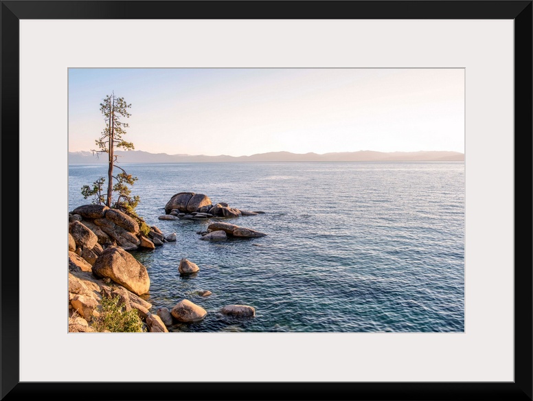 View of Lake Tahoe's rocky shore with mountain landscape in the background in California and Nevada.