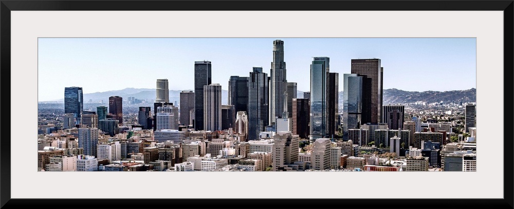 Panoramic photograph of skyscrapers and surrounding buildings of the Los Angeles skyline under a blue sky, California.