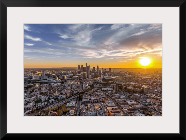 The setting sun visible behind the skyscrapers in the Los Angeles skyline, California.