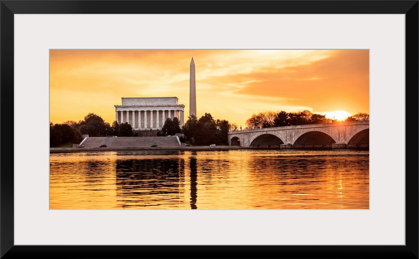 The Lincoln Memorial and Washington Monument seen from the Potomac River with orange clouds at dusk.