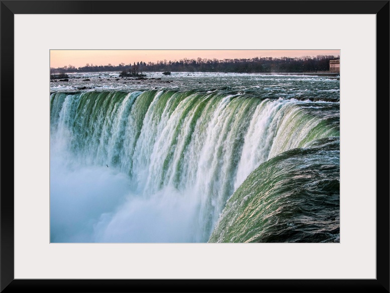 Water cascades down at Horseshoe Falls while dramatic mist ascents to meet the rising sun.