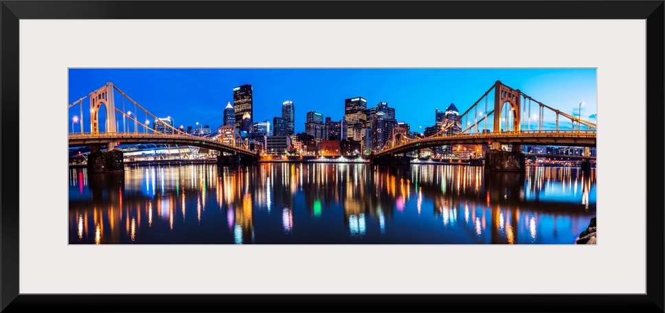 Panoramic photo of downtown Pittsburgh at night with the Rachel Carson Bridge and the Andy Warhol Bridge over the Alleghen...