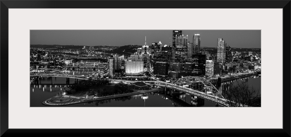 Panoramic photo of the city of Pittsburgh illuminated at night, with Point State Park in the foreground.