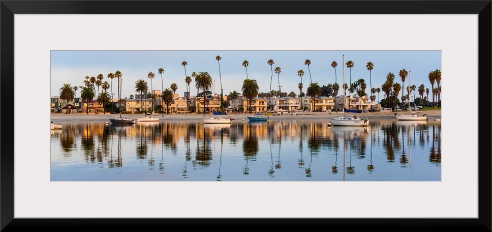 Panoramic photograph of beach houses, palm trees, and boats on the San Diego coast reflecting into the water.