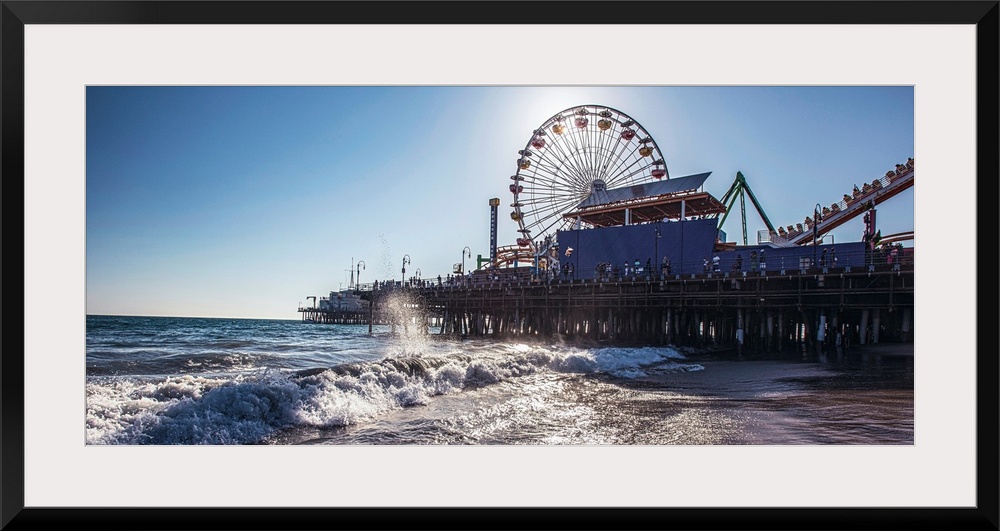 Panoramic photograph of the Santa Monica Pier in Los Angeles, California, with the sun setting right behind the Ferris Wheel.