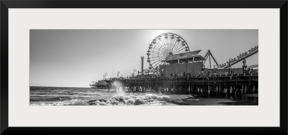 Panoramic photograph of the Santa Monica Pier in Los Angeles, California, with the sun setting right behind the Ferris Wheel.