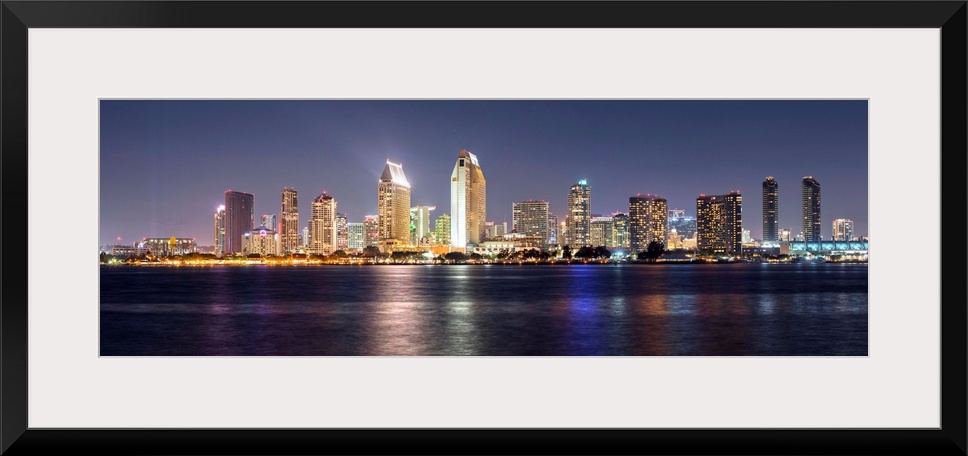 Panoramic photograph of the San Diego, California skyline lit up at night from across the water.