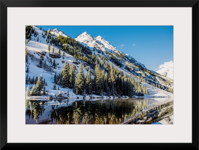 Summer snow on pine trees and the mountain side at the edge of Maroon Lake in the Maroon Bells, Aspen, Colorado.
