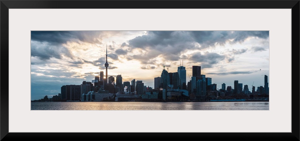 Toronto city skyline under a dramatic sunset with clouds overhead, Ontario, Canada.