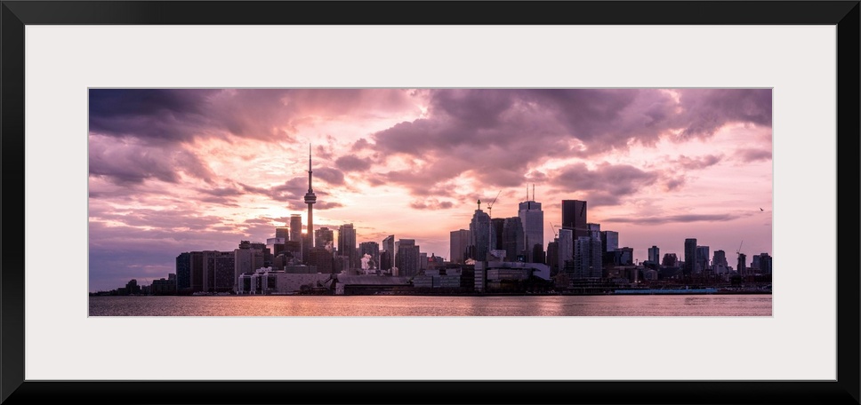 Toronto city skyline under a dramatic sunset with clouds overhead, Ontario, Canada.