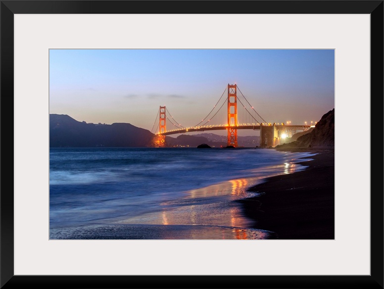 Twilight photograph of the Golden Gate Bridge taken from the shore.