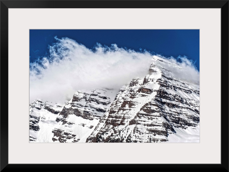 Wind-blown snow on the peaks of the Maroon Bells under a blue sky in Aspen, Colorado.