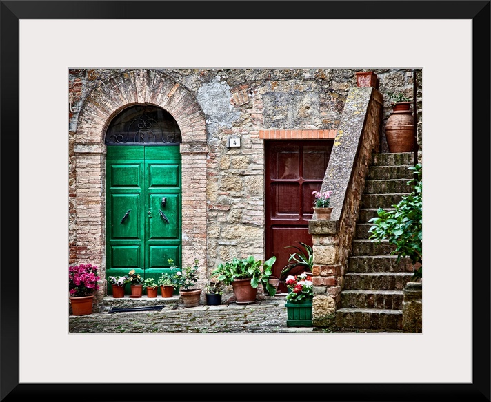 A rustic city street and ancient home built from stone and brick with brightly painted doorways lined with plants in terra...