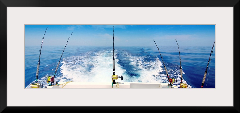 Fishing reels with cast lines off the back of a boat.