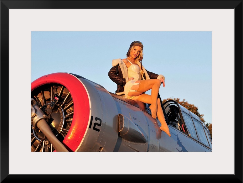 1940's style aviator pin-up girl posing with a vintage World War II T-6 Texan aircraft.