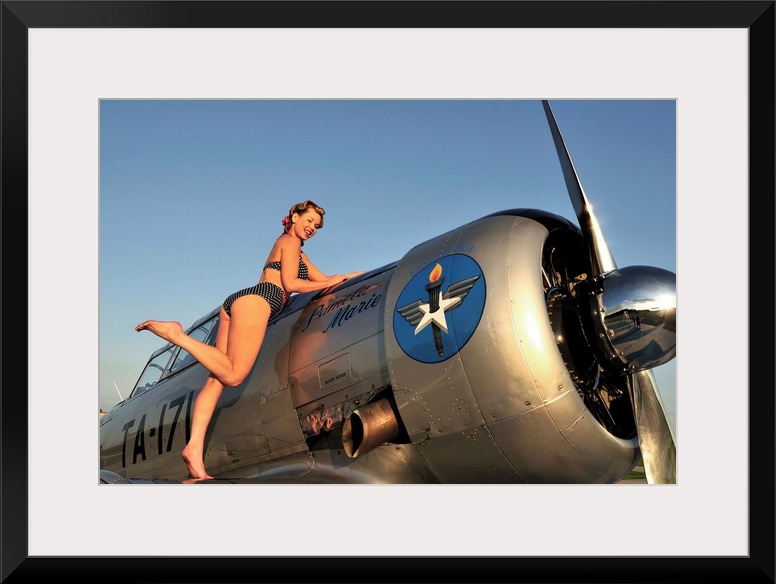 1940's style pin-up girl standing on the wing of a World War II T-6 Texan.