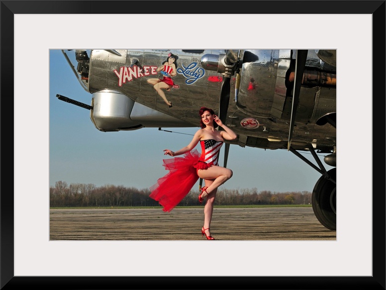 Beautiful 1940's style pin-up girl standing in front of a B-17 bomber.