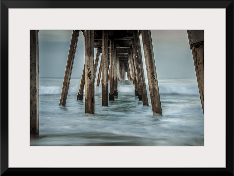 View from below of a wooden pier stretching out into the ocean.