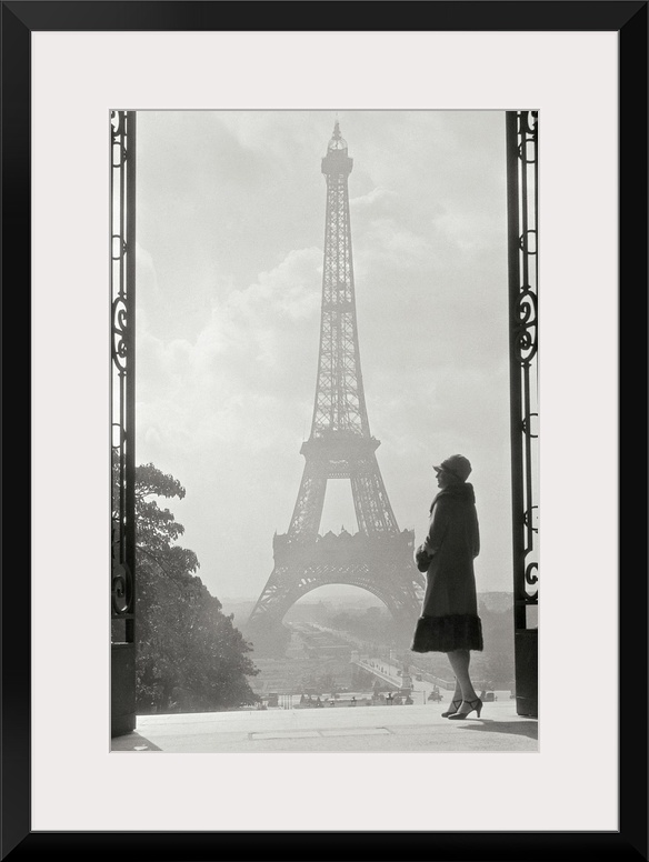 Vintage photograph of a stylish woman standing in an art deco gateway with the Eiffel Tower in the background.