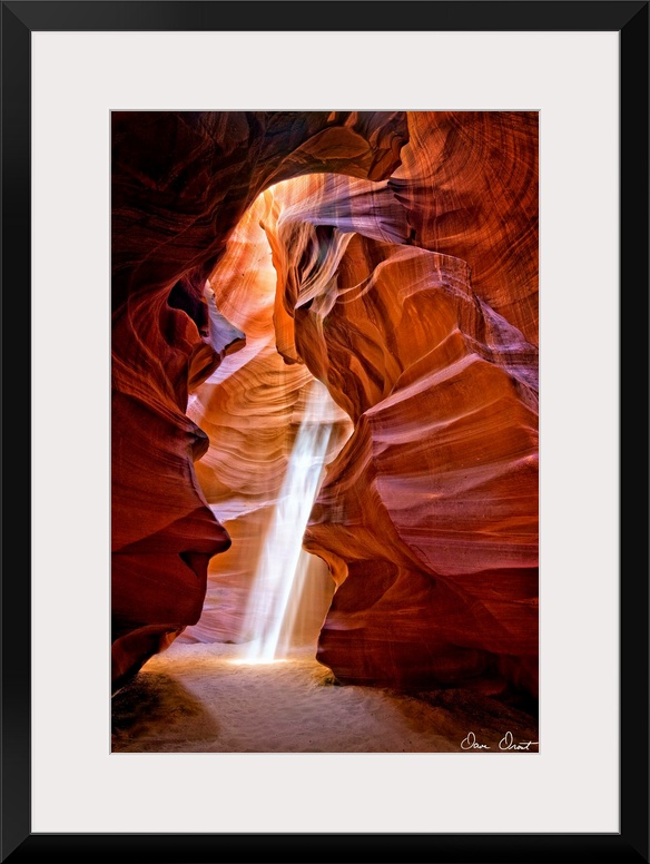 Photograph of the sun shining through the canyon top onto the sand in Antelope Canyon.