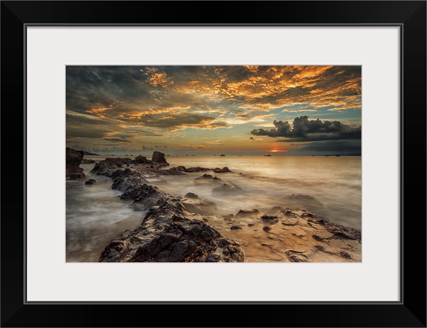 A beach scene under a sky filled with dramatic clouds of sunset.