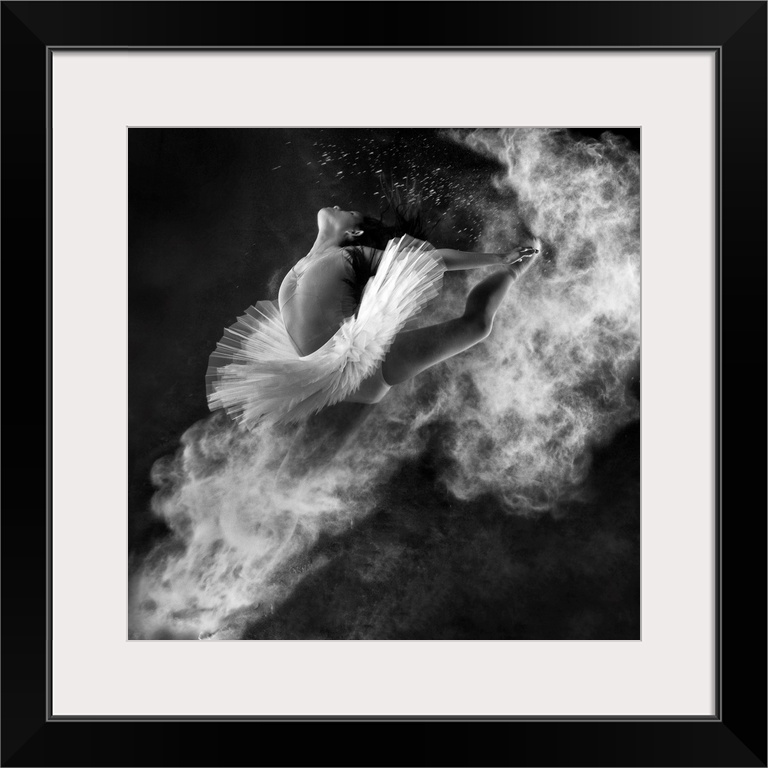 A black and white photograph of a dancer leaping into the air with dust kicking off her hands and feet.