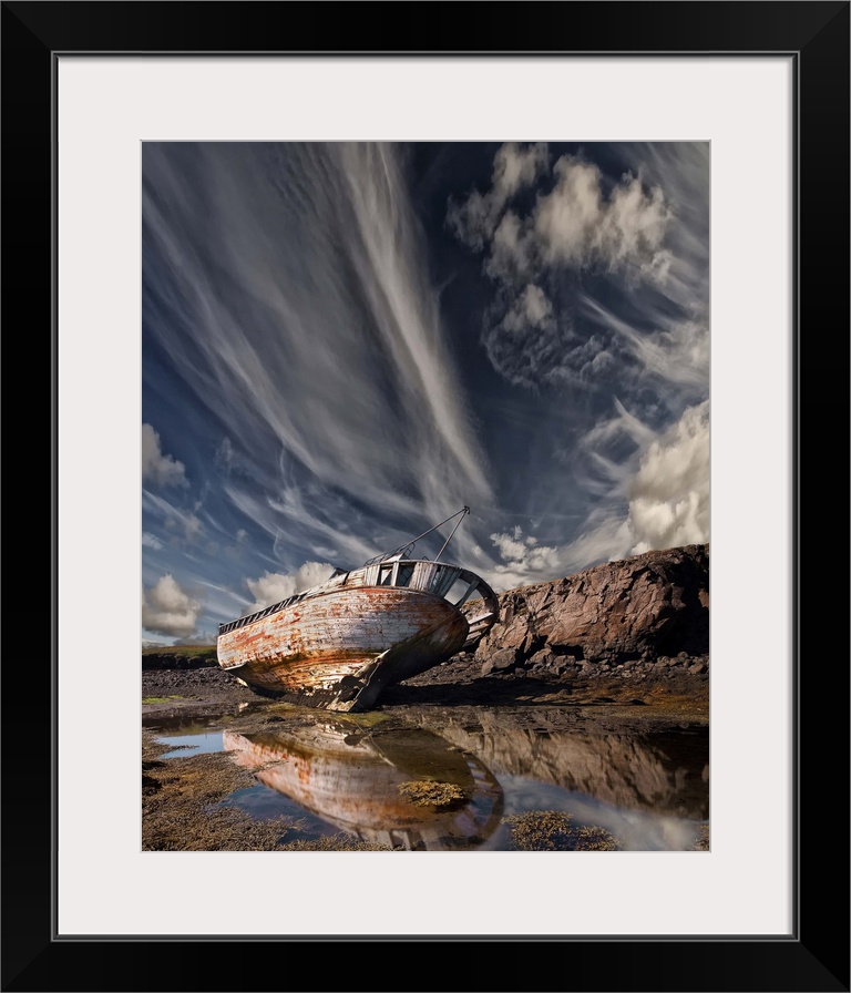 An abandoned and decaying ship beached on land under dramatic clouds in the sky.