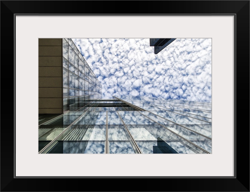 The glass facade of a skyscraper in Brussels reflecting the clouds in the sky.