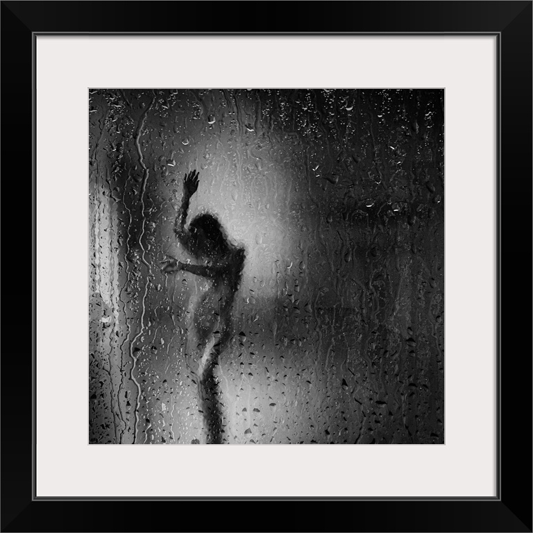 Square black and white fine art photograph of a nude woman through a rainy window glass.