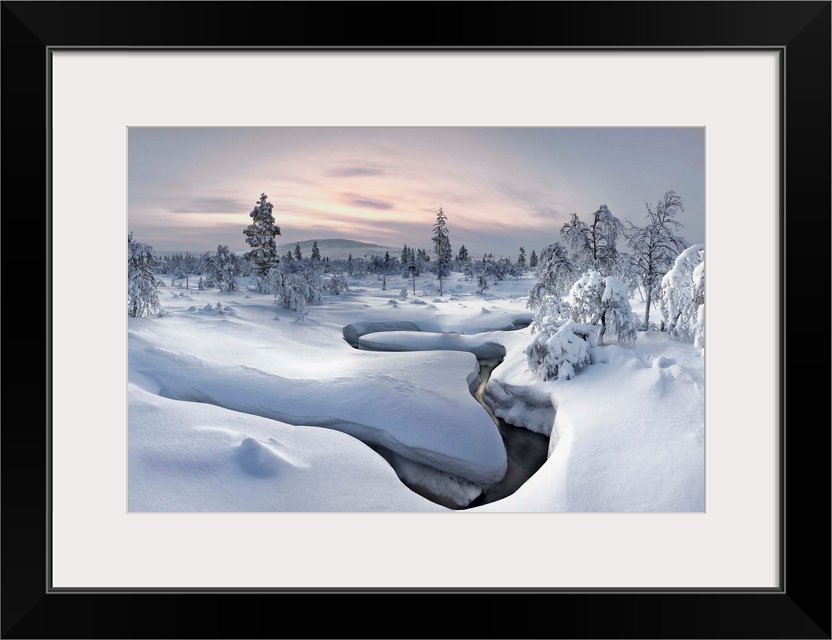 A river cuts a curved path through a landscape with a think blanket of snow in Finland.