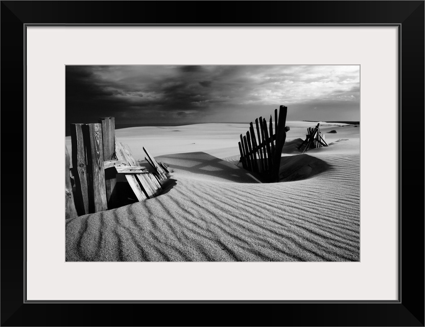 Black and white photograph of a fence at the White Sands dunes in the Curonian Spit.