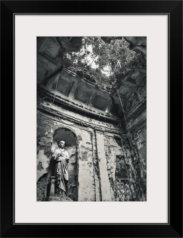 Blue toned black and white photograph of the interior of an old building highlighting a statue, a hole in the ceiling, and...